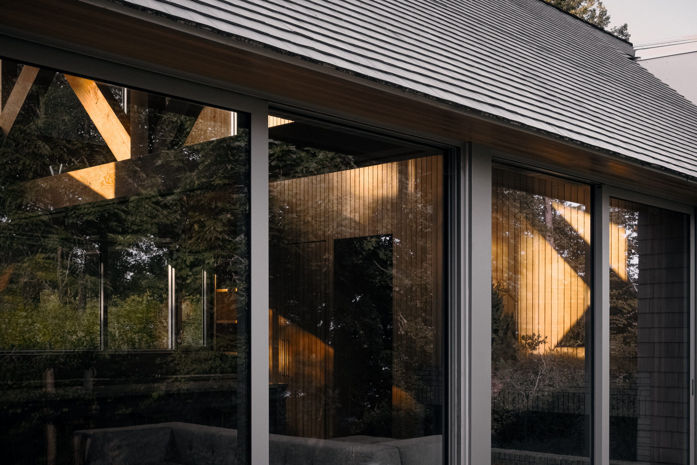 Glazed corner reflecting the timber structure at golden hour