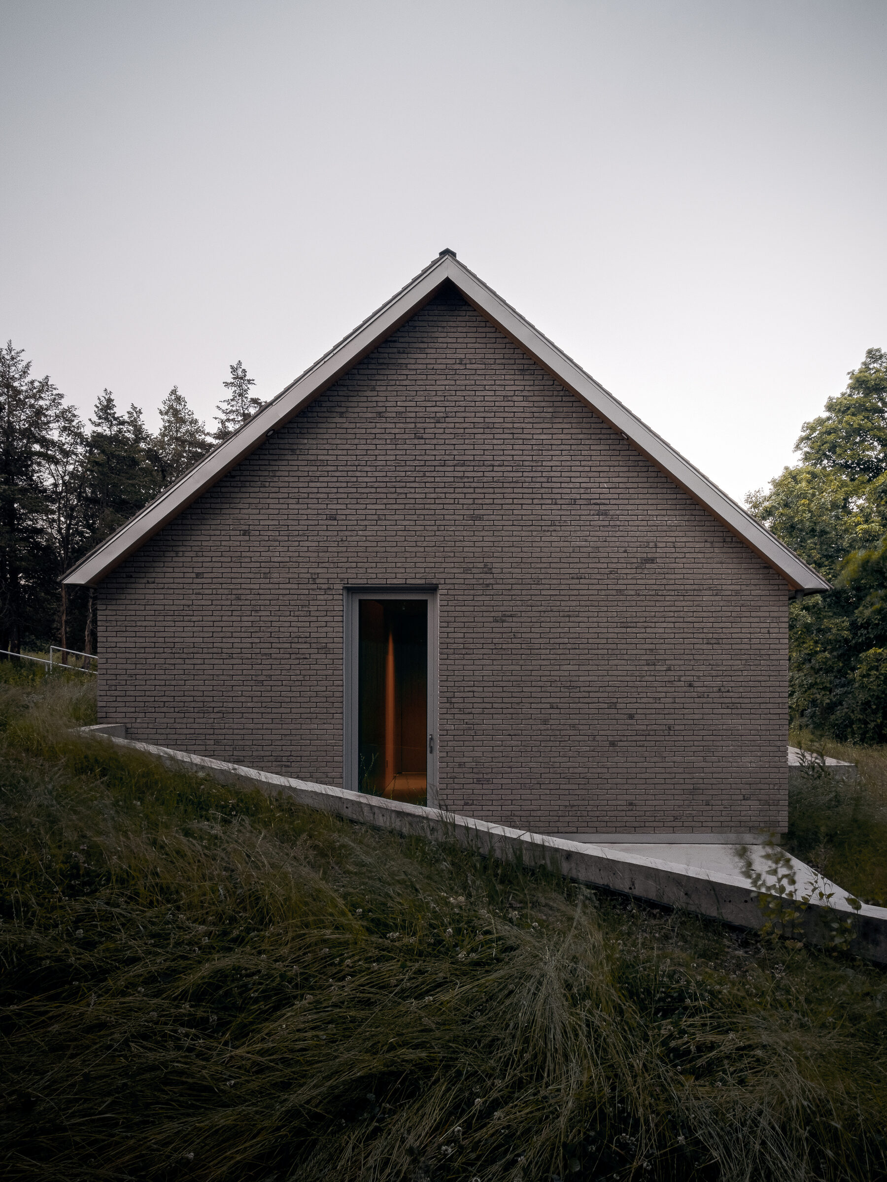 Brick gable with lit doorway at dusk